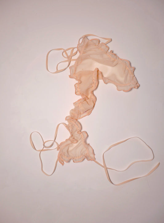 Delicate pale peach tie-side chiffon thong with soft adjustable elastic ties, semi-sheer polyester fabric, feminine intimate design, handcrafted in London luxury lingerie